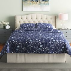 a bed with blue and white bedspread sitting on top of a wooden floor