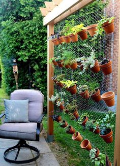 an outdoor garden with potted plants and a chair in front of the trellis