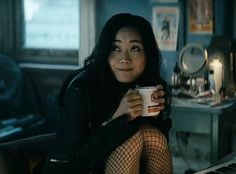 a woman in fishnet stockings is holding a coffee cup and looking at the camera