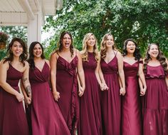 a group of women standing next to each other in long dresses smiling at the camera