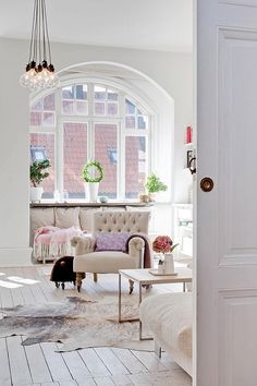 a living room filled with furniture and a chandelier hanging from the ceiling next to a window