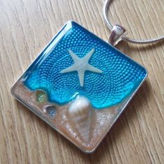 a glass pendant with a starfish and seashell on it sitting on a wooden table