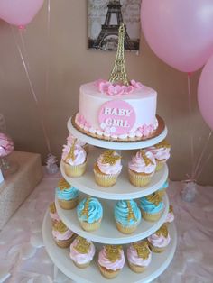 a cake and cupcakes on a table with pink and blue decorations in front of the eiffel tower