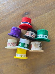 several different colored hats are sitting on a wooden table with one hat in the middle