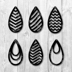 four black and white tear shaped metal wall hangings on a wooden background with the word,