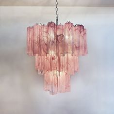 a pink chandelier hanging from a ceiling in a room with white walls and flooring