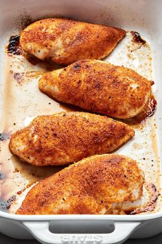 three pieces of chicken in a white casserole dish