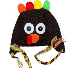 a crocheted hat with a turkey on it's face and colorful feathers