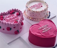 three heart shaped birthday cakes sitting on top of a white table next to each other