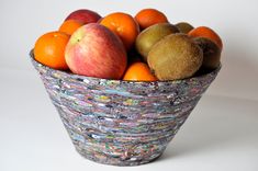 a bowl filled with fruit sitting on top of a white table next to an apple