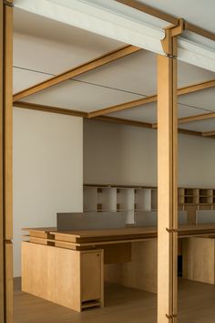 an empty office space with wooden desks and open shelves on the wall behind them