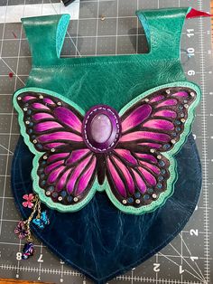 Lepidolite cabochon, hand painted pyrography on tooling goatskin butterfly with a slight iradescent mica gloss finish, with 2 dozen rhinestone rivets (not glued, real rivets bag measures roughly 12 inches tall tip to tip and 8.5 inches wide, with side gussets that accordion open to cavernously deep. Tapered loops accommodate a 2 inch wide belt with ease. Closure with two large magnetic snaps. Please note that snaps do not close when bag is empty laying flat on a table; this is by design, bag is Painted Pyrography, Butterfly Belt, Leather Butterfly, Design Bag, Hand Painted Leather, Painting Leather, Butterfly Charm, Wide Belt, Adult Costumes