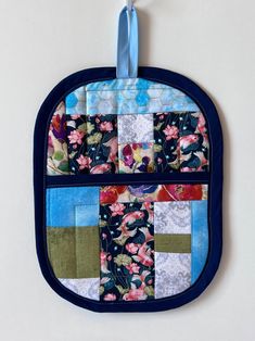 an oven mitt hanging from a hook on a white wall with flowers and blue trim