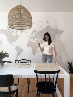 a woman standing at a table in front of a world map