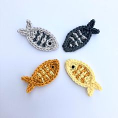 four crocheted fish sitting on top of a white table