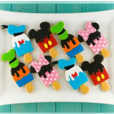 mickey and minnie mouse decorated cookies on a white platter with blue wood planks