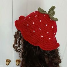 a close up of a person wearing a knitted strawberry hat