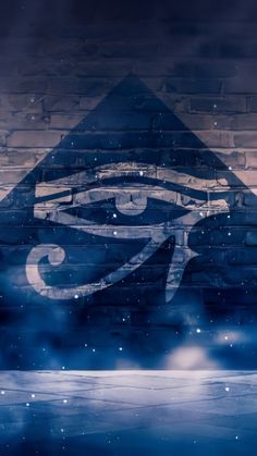 an all seeing symbol painted on a brick wall in the night sky with snow falling around it