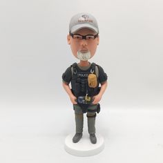 a figurine of a police officer is posed on a white base with a gray cap and glasses