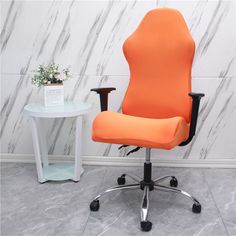 an orange office chair next to a white table with a potted plant on it