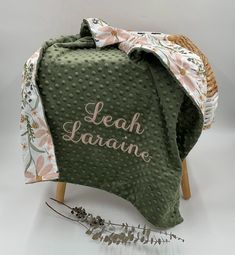 a green blanket with the words leah lananie on it next to a plant