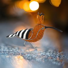 a beaded bird sitting on top of a table next to a yellow and white light