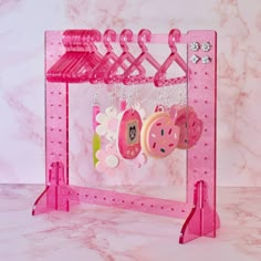 a pink toy rack with clothes hanging from it's hooks and clips on the hangers