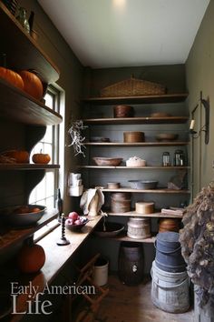 an old fashioned kitchen with many pots and pans on the shelves in front of it