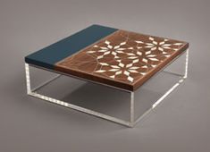 a coffee table with an intricate design on the top and bottom, sitting in front of a gray background