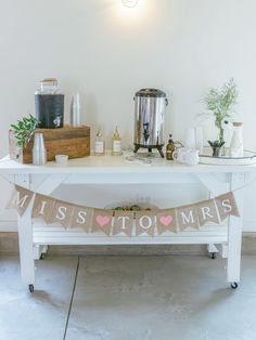 a white table topped with a bunting banner next to a blender and potted plant