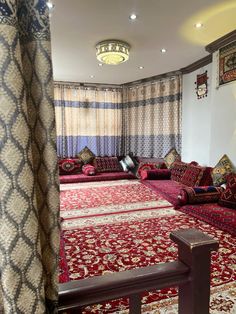 a living room filled with lots of red couches and rugs on the floor