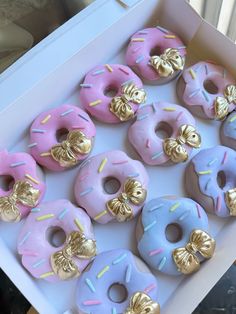 there are many donuts in the box with gold bows on them and sprinkles