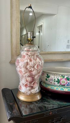 a vase filled with pink flowers sitting on top of a table next to a mirror