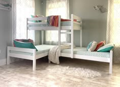 two white bunk beds sitting next to each other on top of a hard wood floor