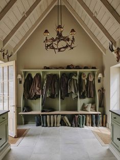 a room filled with lots of coats and shoes on top of wooden shelves under a chandelier