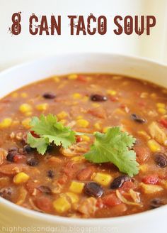 a white bowl filled with mexican soup and garnished with cilantro, black beans, corn, and lime