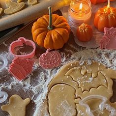 some cookies and pumpkins are sitting on a table with cookie cutters in front of them