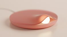 a pink lamp with a white light shining on it's side and an oval shaped base