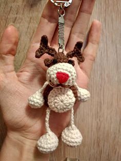 a hand holding a crocheted keychain with a stuffed animal on it