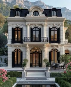 a large white house with lots of windows and balconies next to a pool