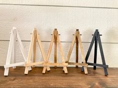 four wooden easels are lined up on a wood surface, with one leaning against the wall