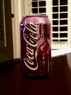 a can of coca - cola sitting on top of a table next to a window