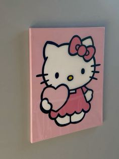 a pink hello kitty wall hanging on the side of a wall with a heart in it