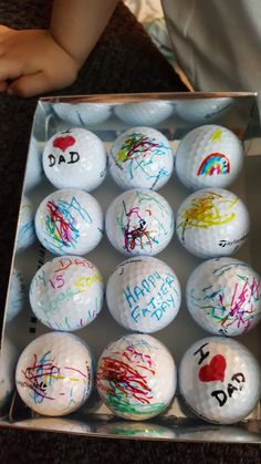 a box filled with lots of golf balls covered in graffiti