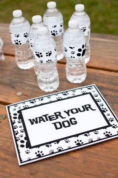 water bottles are sitting on top of a wooden table with a sign that says, water your dog