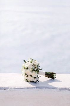 a bouquet of white flowers sitting on the edge of a wall next to some water