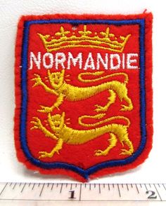 a red and blue patch with the word normandie on it, next to a ruler