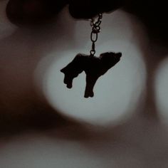 a black and white photo of a person's hand holding a dog charm