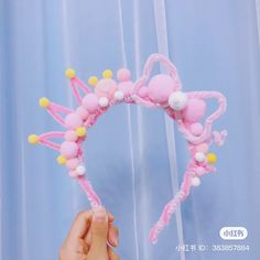 a person is holding a pink headband with pom poms