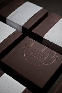 several brown and white business cards are stacked on top of each other, with the letter e in gold